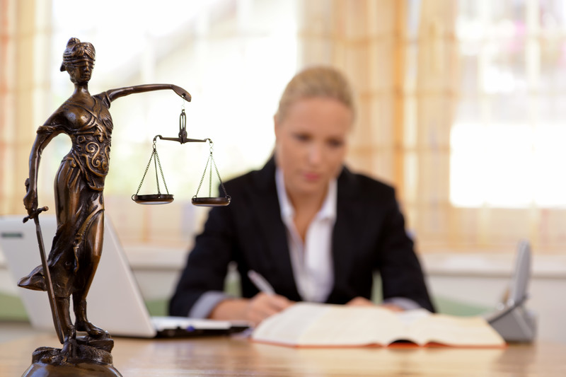 Lawyer working and referring to legal text with a small statue of justice in the forefront