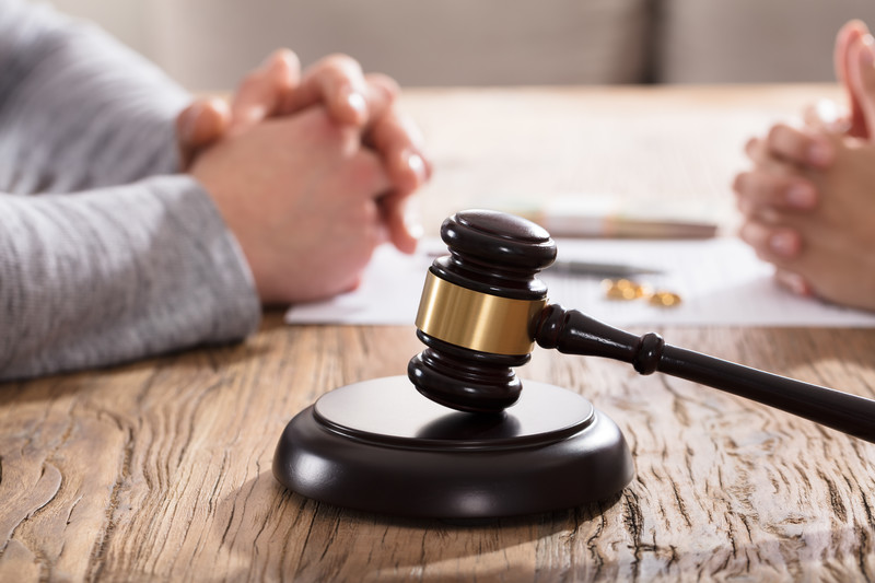 A lawyer and a client talking across a table about Criminal defence case, with a gavel in front